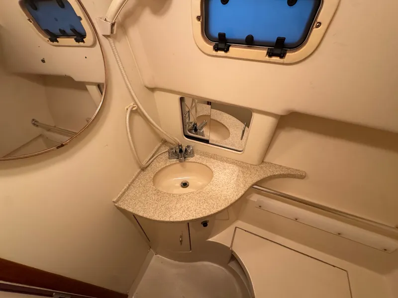 Slide: The Image of 1999 Mainship Pilot 30 Sedan bathroom with sink, mirror, and porthole window. - 25