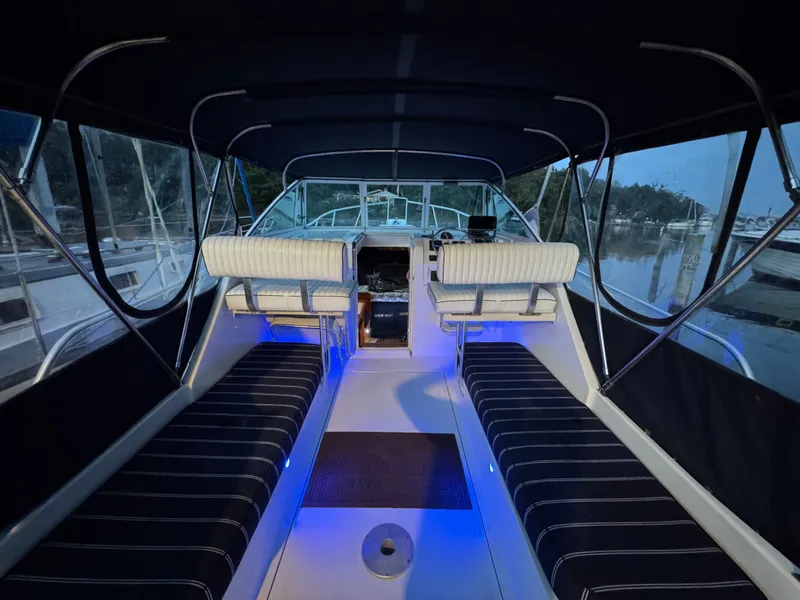 Slide: The Image of 1999 Mainship Pilot 30 Sedan interior with blue lighting, featuring striped seating and a covered helm. - 31