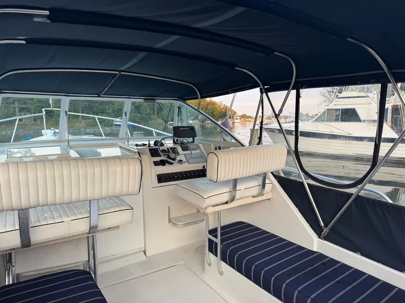 Slide: The Image of 1999 Mainship Pilot 30 Sedan interior with seating and steering wheel, docked at marina. - 8