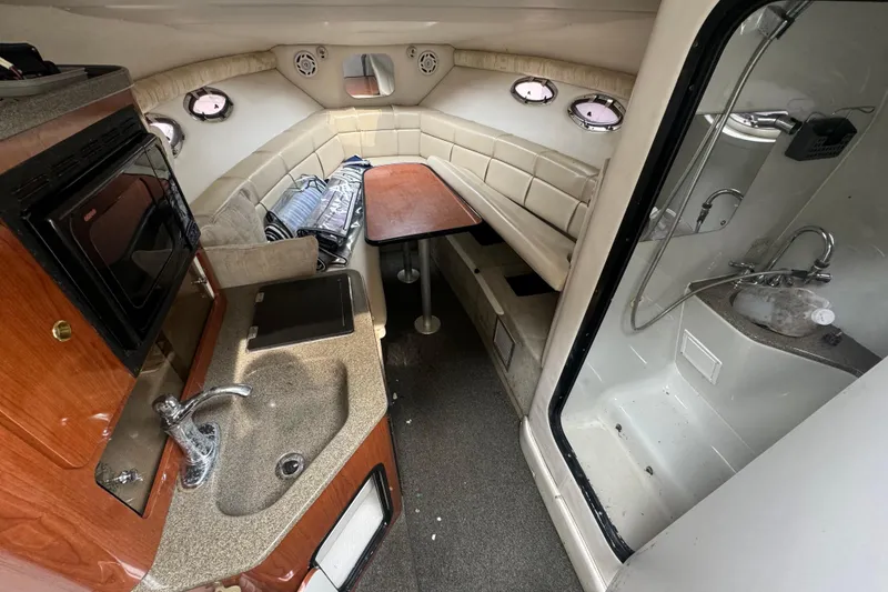 Slide: The Image of 2003 Crownline 266 BR boat interior with kitchenette, seating, and shower area. - 5