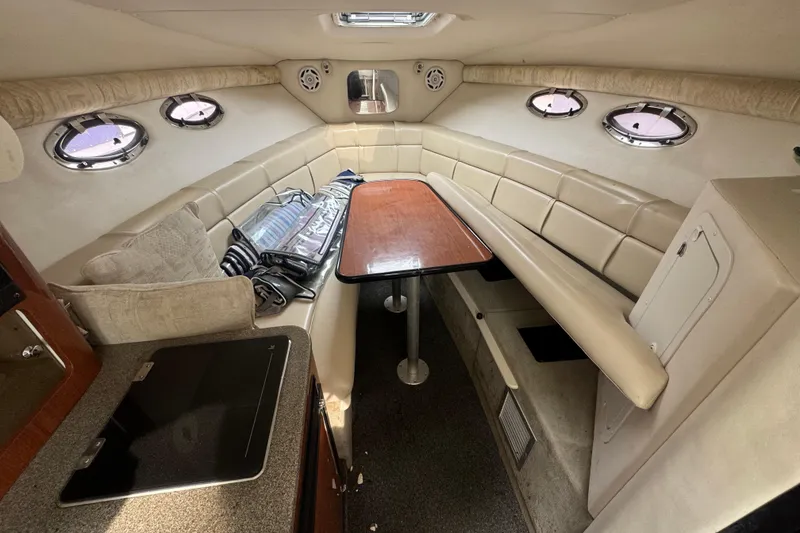 Slide: The Image of Interior of a 2003 Crownline 266 BR boat with beige seating and wooden table. - 8