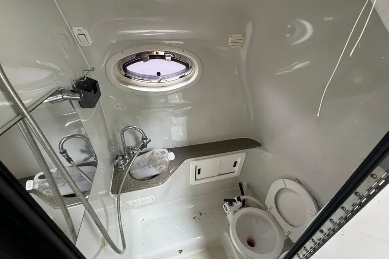 Slide: The Image of 2003 Crownline 266 BR boat bathroom with sink, toilet, and porthole window. - 9