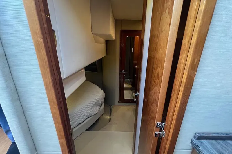 Slide: The Image of 2015 Sea Ray 470 Sundancer cabin interior with cozy bed and wooden door. - 29