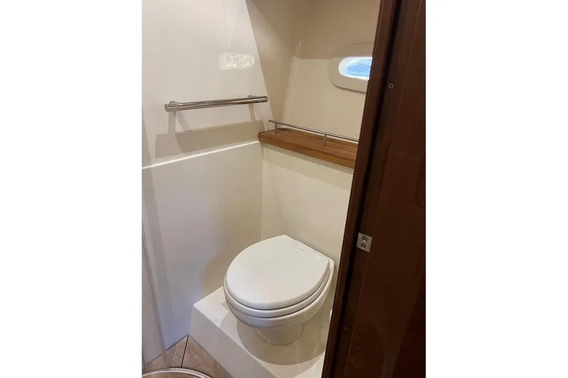 Slide: The Image of Bathroom interior of 2015 Sea Ray 470 Sundancer yacht, featuring a compact toilet and window. - 34