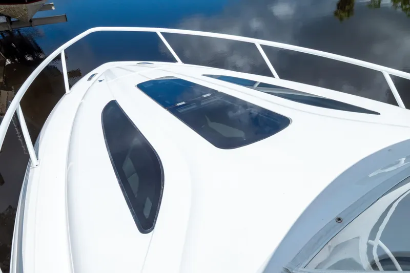 Slide: The Image of 2023 Intrepid 345 Valor boat deck with sleek windows and railing, reflecting on water. - 129