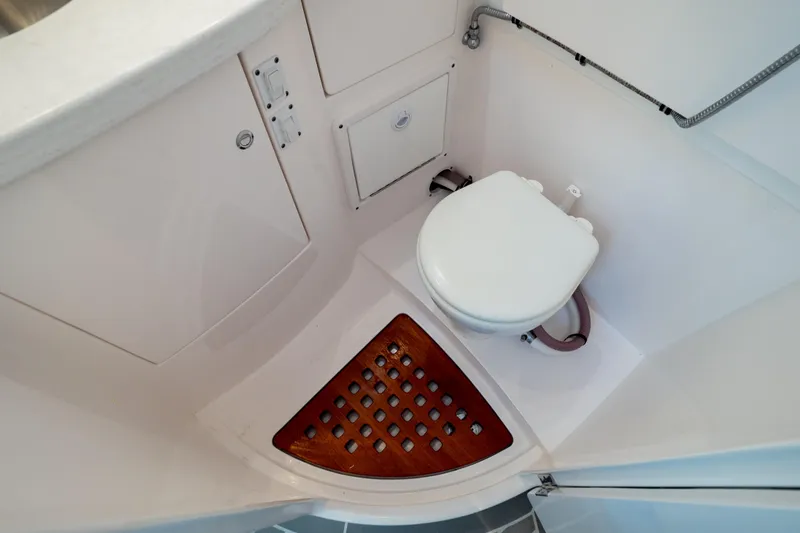 Slide: The Image of 2023 Intrepid 345 Valor boat bathroom with white toilet and wooden floor mat. - 13