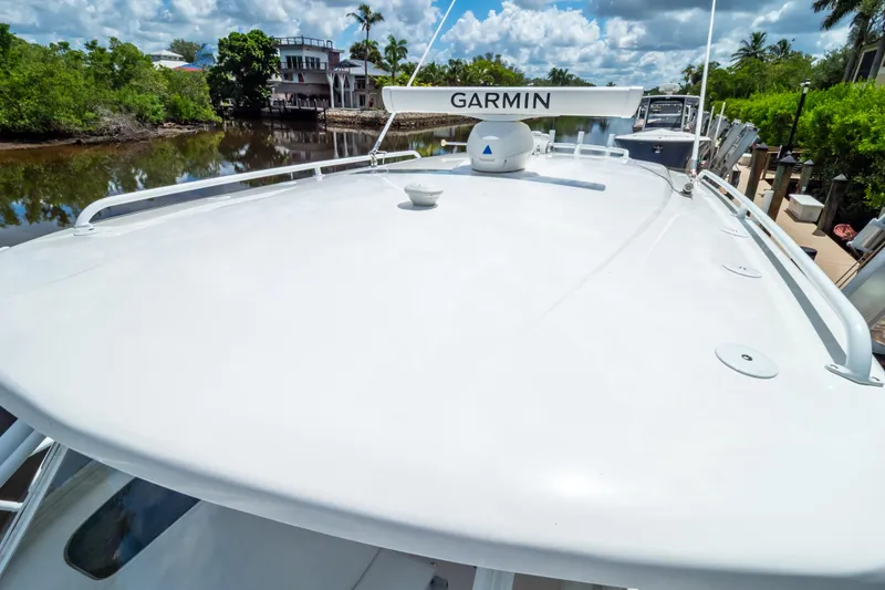 Slide: The Image of 2023 Intrepid 345 Valor boat with Garmin radar, docked near lush greenery. - 131
