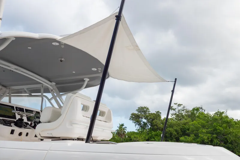 Slide: The Image of 2023 Intrepid 345 Valor boat with canopy, helm, and lush greenery background. - 134