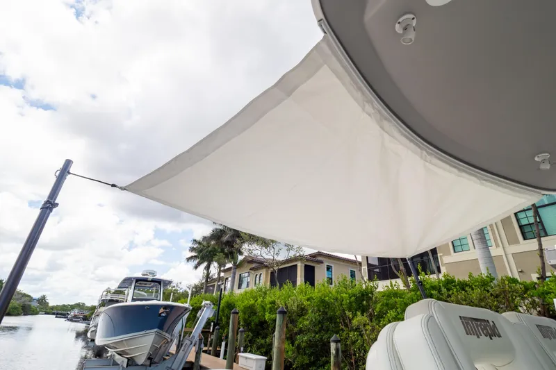 Slide: The Image of 2023 Intrepid 345 Valor boat with sunshade, docked near waterfront homes. - 135
