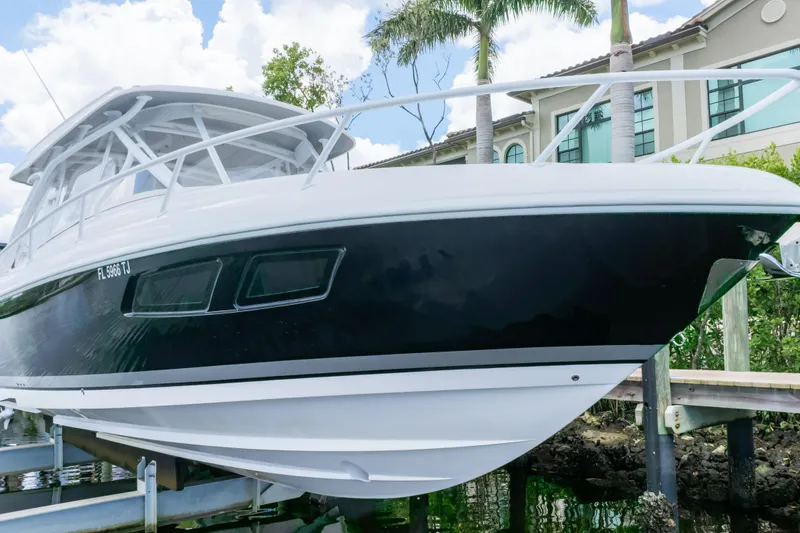 Slide: The Image of 2023 Intrepid 345 Valor boat docked near waterfront home, under a clear sky. - 16