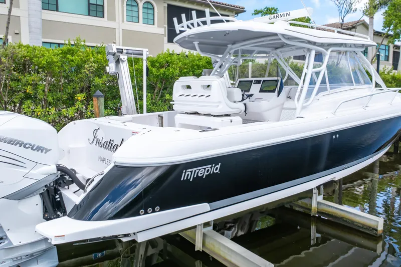 Slide: The Image of 2023 Intrepid 345 Valor boat with Mercury engines, docked near luxury homes. - 20