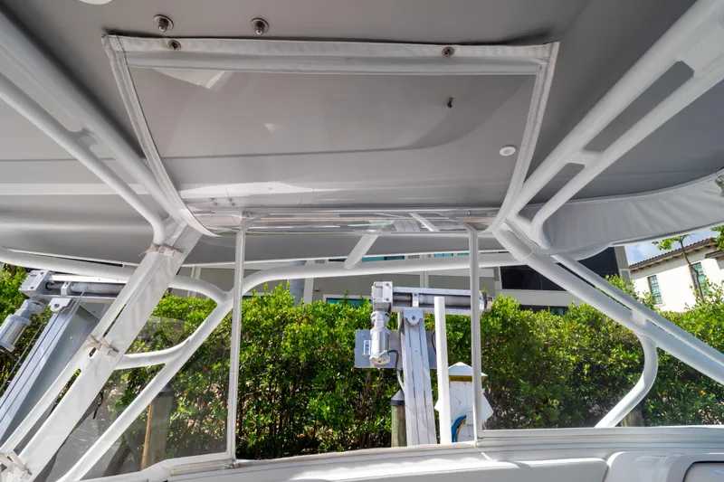 Slide: The Image of 2023 Intrepid 345 Valor boat canopy and frame detail with lush greenery background. - 83