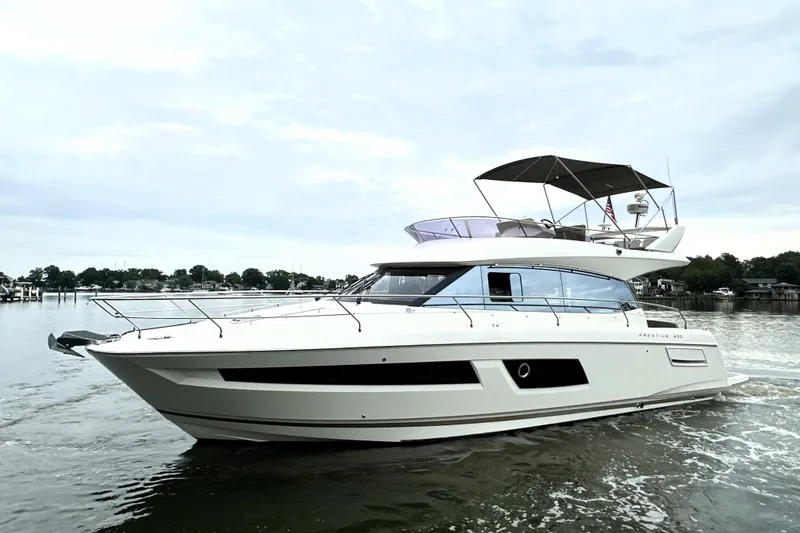 Slide: The Image of 2014 Prestige 450 yacht cruising on calm waters under a cloudy sky. - 11