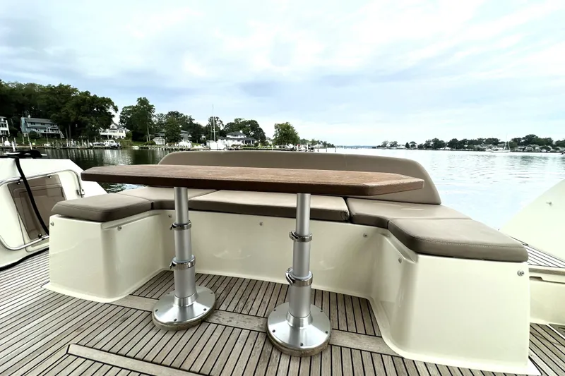 Slide: The Image of 2014 Prestige 450 yacht deck with seating and table, overlooking serene waterfront homes. - 15