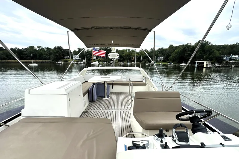Slide: The Image of Flybridge of 2014 Prestige 450 yacht with seating, helm, and American flag on calm water. - 20