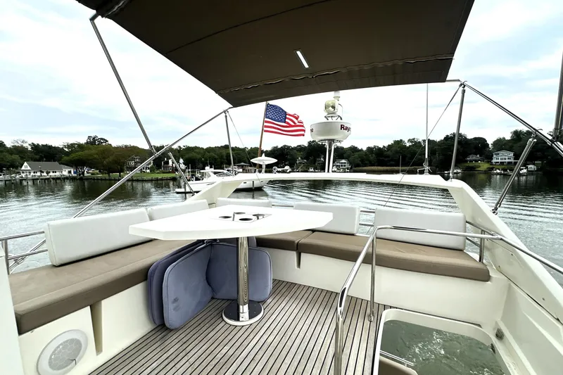 Slide: The Image of 2014 Prestige 450 yacht deck with seating, table, and American flag on calm water. - 21