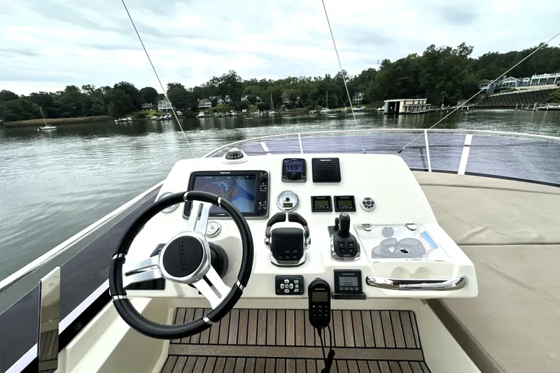 Slide: The Image of Cockpit view of a 2014 Prestige 450 yacht with navigation controls and serene water backdrop. - 28