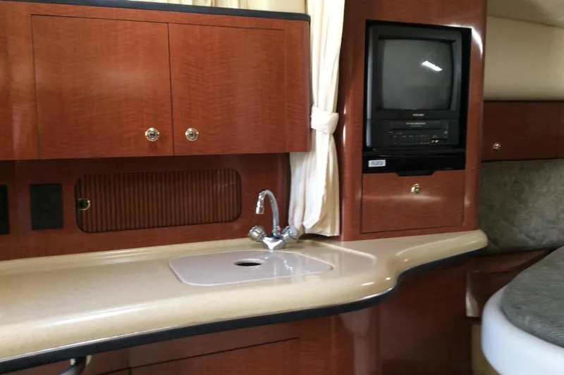 Slide: The Image of 2003 Sea Ray 320 Sundancer interior with sink, TV, and wooden cabinetry. - 17