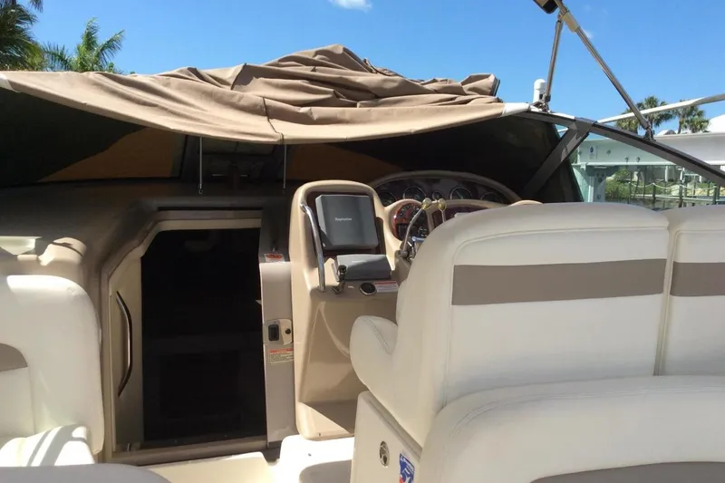 Slide: The Image of 2003 Sea Ray 320 Sundancer cockpit with beige seating and navigation equipment under a canopy. - 29