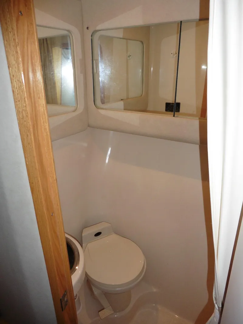 Slide: The Image of 1997 Sea Ray 440 Express Bridge bathroom with toilet and mirrored cabinets. - 18