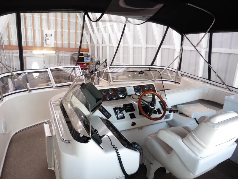 Slide: The Image of 1997 Sea Ray 440 Express Bridge cockpit with steering wheel and navigation controls in a covered dock. - 35