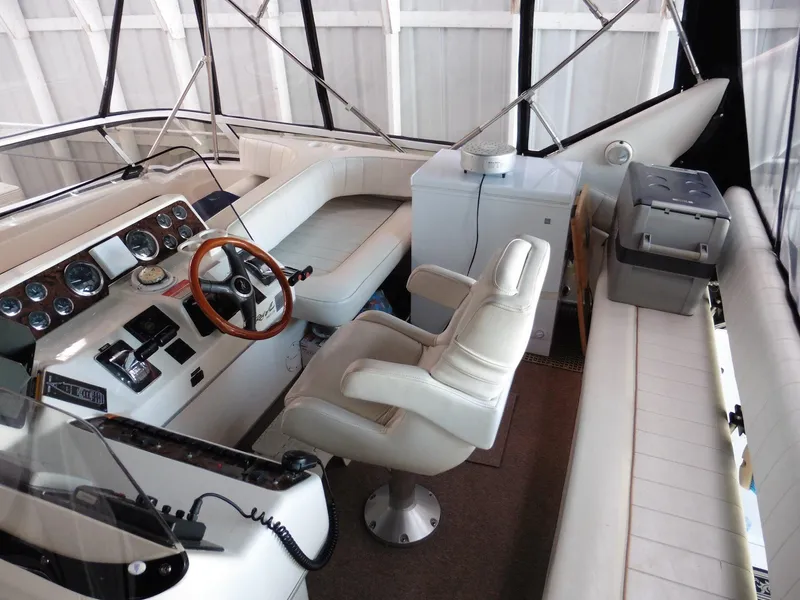 Slide: The Image of 1997 Sea Ray 440 Express Bridge cockpit with white seating and wooden steering wheel. - 36