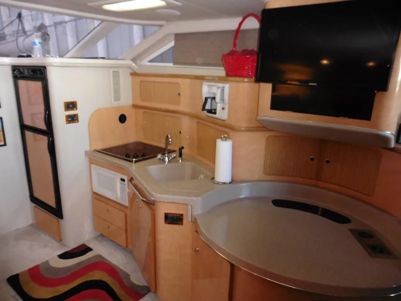Slide: The Image of 1997 Sea Ray 440 Express Bridge interior with kitchenette, sink, and TV. - 4