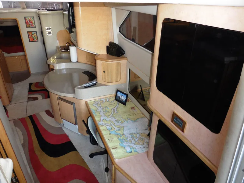 Slide: The Image of 1997 Sea Ray 440 Express Bridge interior with map table and modern amenities. - 8