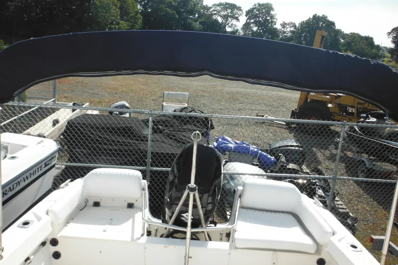 Slide: The Image of 1998 Boston Whaler 20 Ventura Bowrider with canopy, parked in a fenced area. - 33