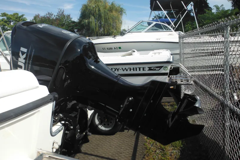 Slide: The Image of 1998 Boston Whaler 20 Ventura Bowrider with Suzuki outboard motor, parked near a fence. - 6