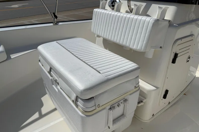 Slide: The Image of 2005 Boston Whaler 170 Montauk interior seating with white cushioned bench and storage. - 14