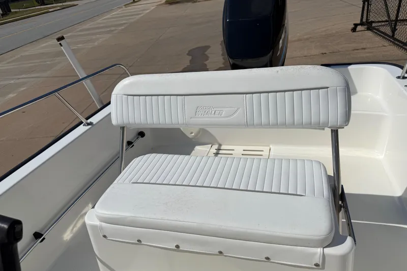 Slide: The Image of 2005 Boston Whaler 170 Montauk boat seat, white upholstery, outdoor setting. - 17