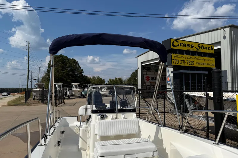 Slide: The Image of 2005 Boston Whaler 170 Montauk boat at dealership, blue canopy, sunny day, Grass Shack sign visible. - 25