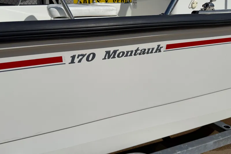 Slide: The Image of 2005 Boston Whaler 170 Montauk boat side view with red stripe detailing. - 26