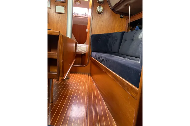 Slide: The Image of Interior of 1985 Beneteau First 345 sailboat with wooden flooring and blue seating. - 14