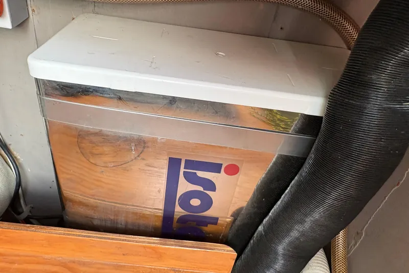 Slide: The Image of Boat interior detail of a 1985 Beneteau First 345, featuring storage compartment and hoses. - 20