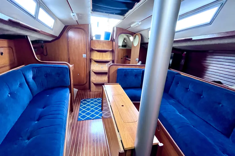 Slide: The Image of Interior of 1985 Beneteau First 345 sailboat with blue seating and wooden finishes. - 9