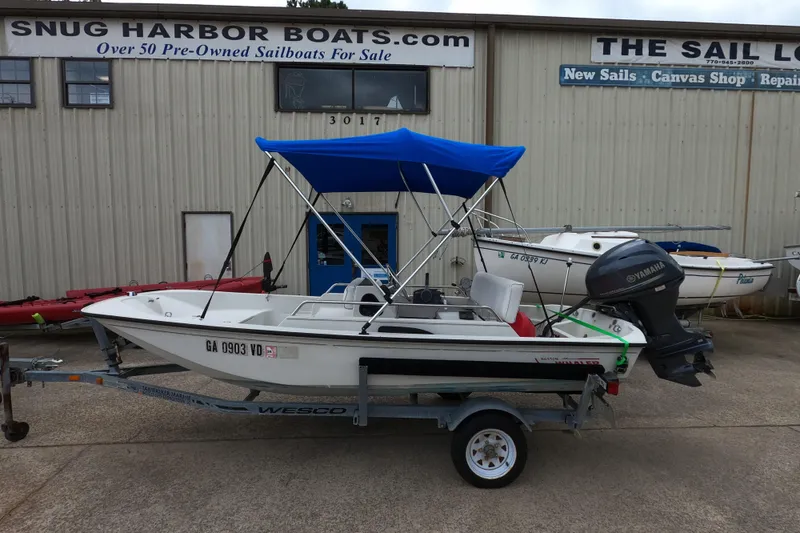 The Image of 1992 Boston Whaler 13 GLS boat with blue canopy on trailer, parked outside Snug Harbor Boats. - 0