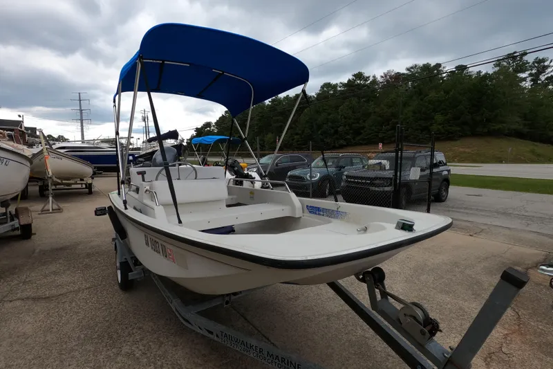 Slide: The Image of 1992 Boston Whaler 13 GLS boat with blue canopy on trailer, parked outdoors. - 2