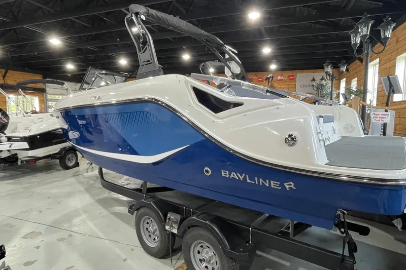 Slide: The Image of 2026 Bayliner D22I boat in showroom, blue and white design, on trailer. - 3