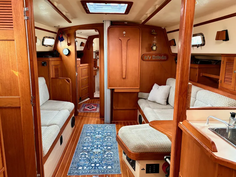 Slide: The Image of Interior of a 2000 Island Packet 40 sailboat, featuring cozy seating and elegant wood finishes. - 19