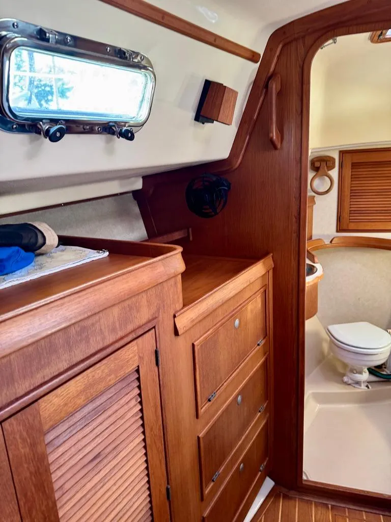 Slide: The Image of Interior of 2000 Island Packet 40 sailboat, featuring wooden cabinetry and a compact bathroom. - 21