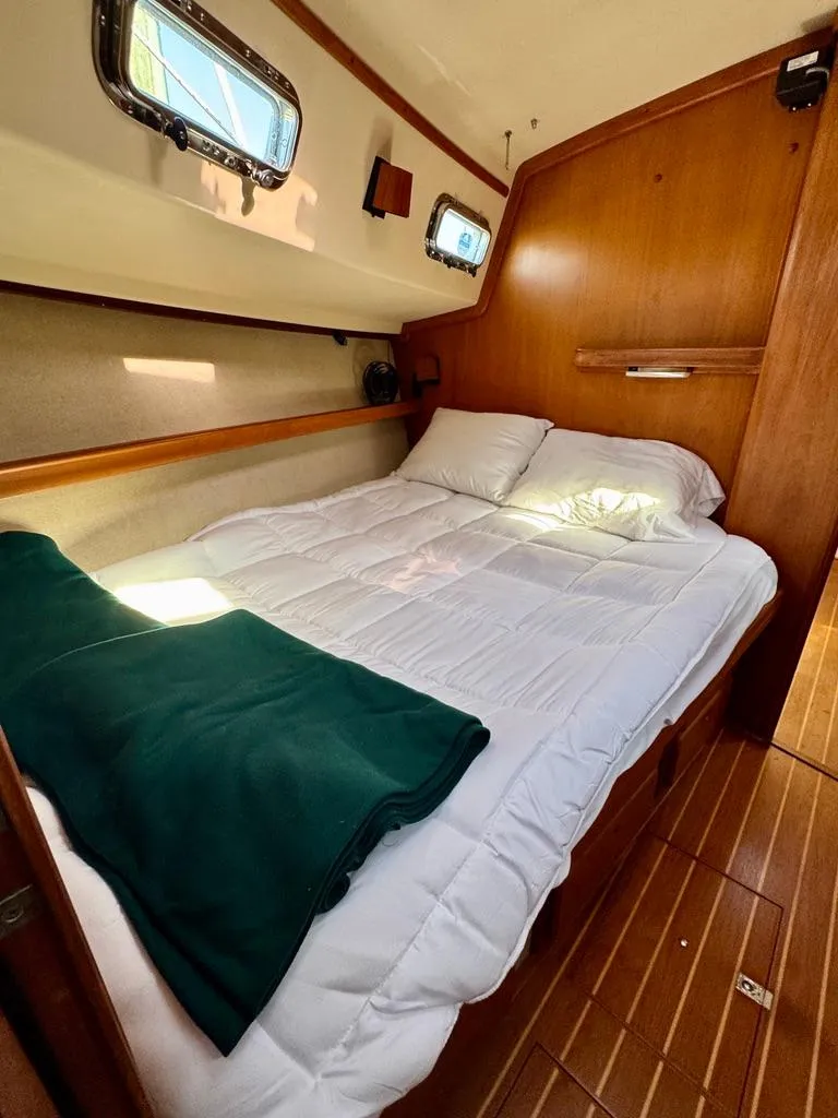 Slide: The Image of Cozy cabin interior of 2000 Island Packet 40 sailboat with bed and wooden accents. - 24