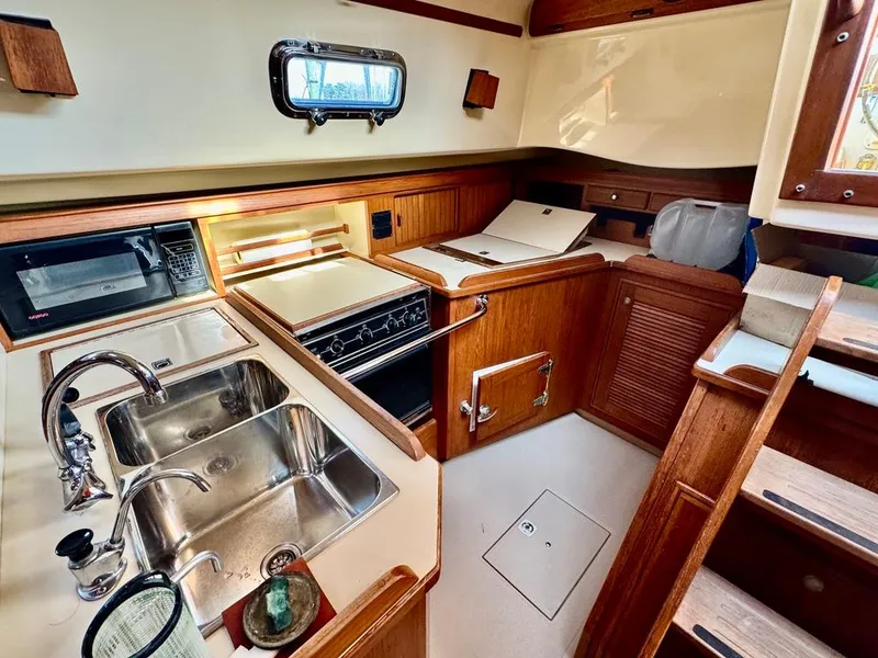 Slide: The Image of Island Packet 40 yacht kitchen interior, 2000 model, featuring wood cabinetry and stainless steel sink. - 32