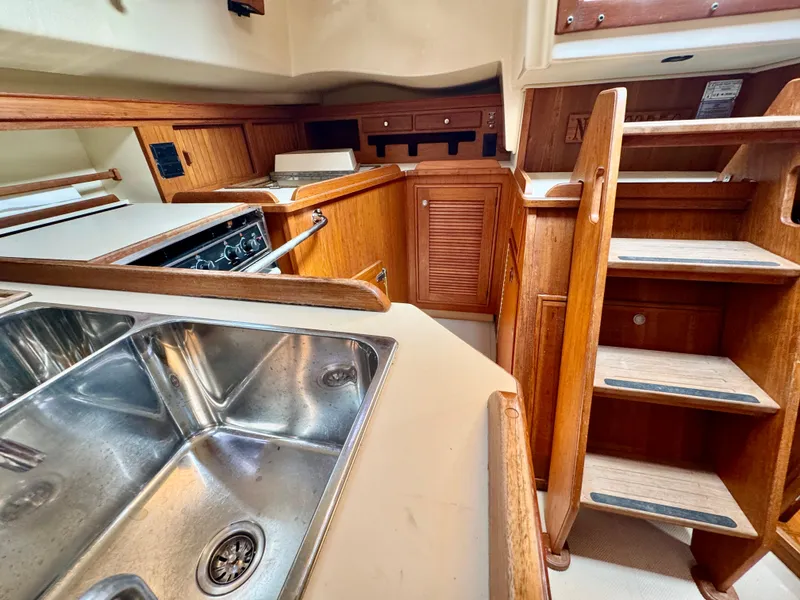 Slide: The Image of Interior of 2000 Island Packet 40 sailboat, featuring a kitchen sink and wooden cabinetry. - 34