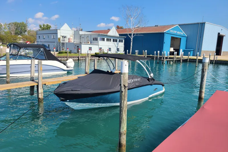 Slide: The Image of 2022 Cobalt CS22 boat docked at marina with blue water and clear sky. - 2