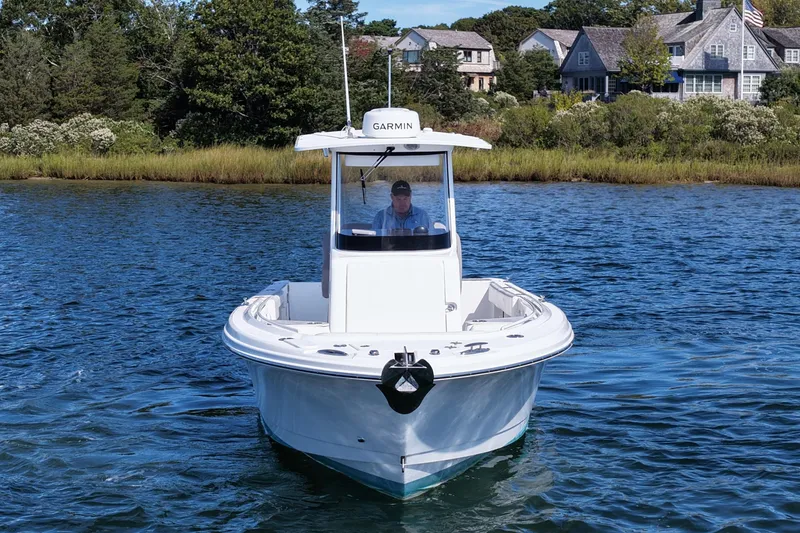 Slide: The Image of 2023 Edgewater 262CC boat on water near shoreline with houses in background. - 10