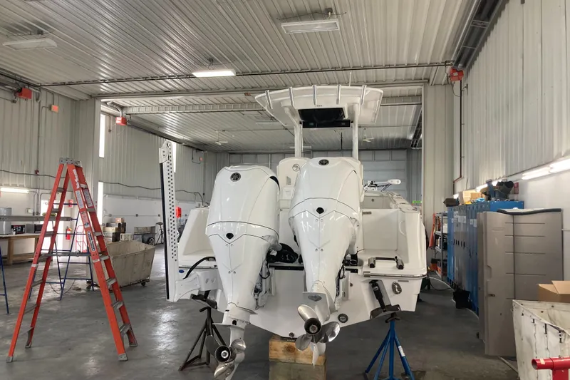 Slide: The Image of 2023 Edgewater 262CC boat in a workshop with twin outboard engines. - 22