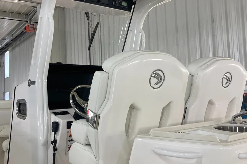 Slide: The Image of 2023 Edgewater 262CC boat interior with white captain seats and steering wheel. - 24