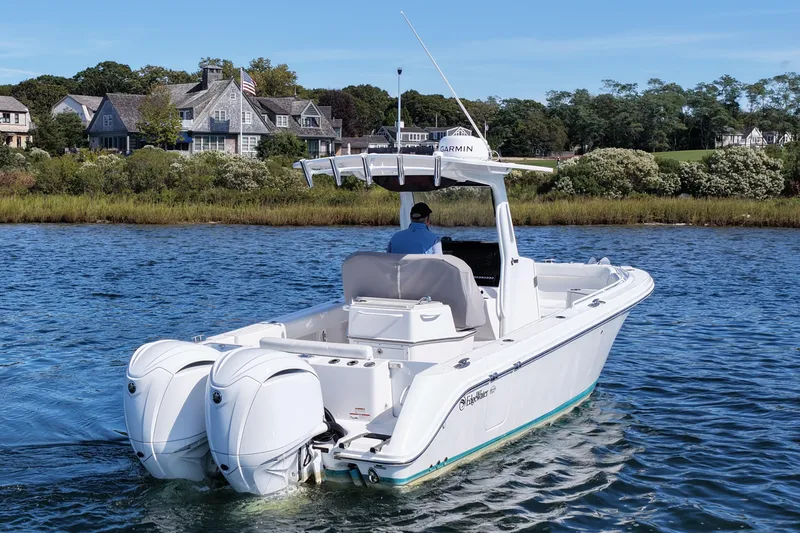 Slide: The Image of 2023 Edgewater 262CC boat cruising on a scenic lake with houses in the background. - 3